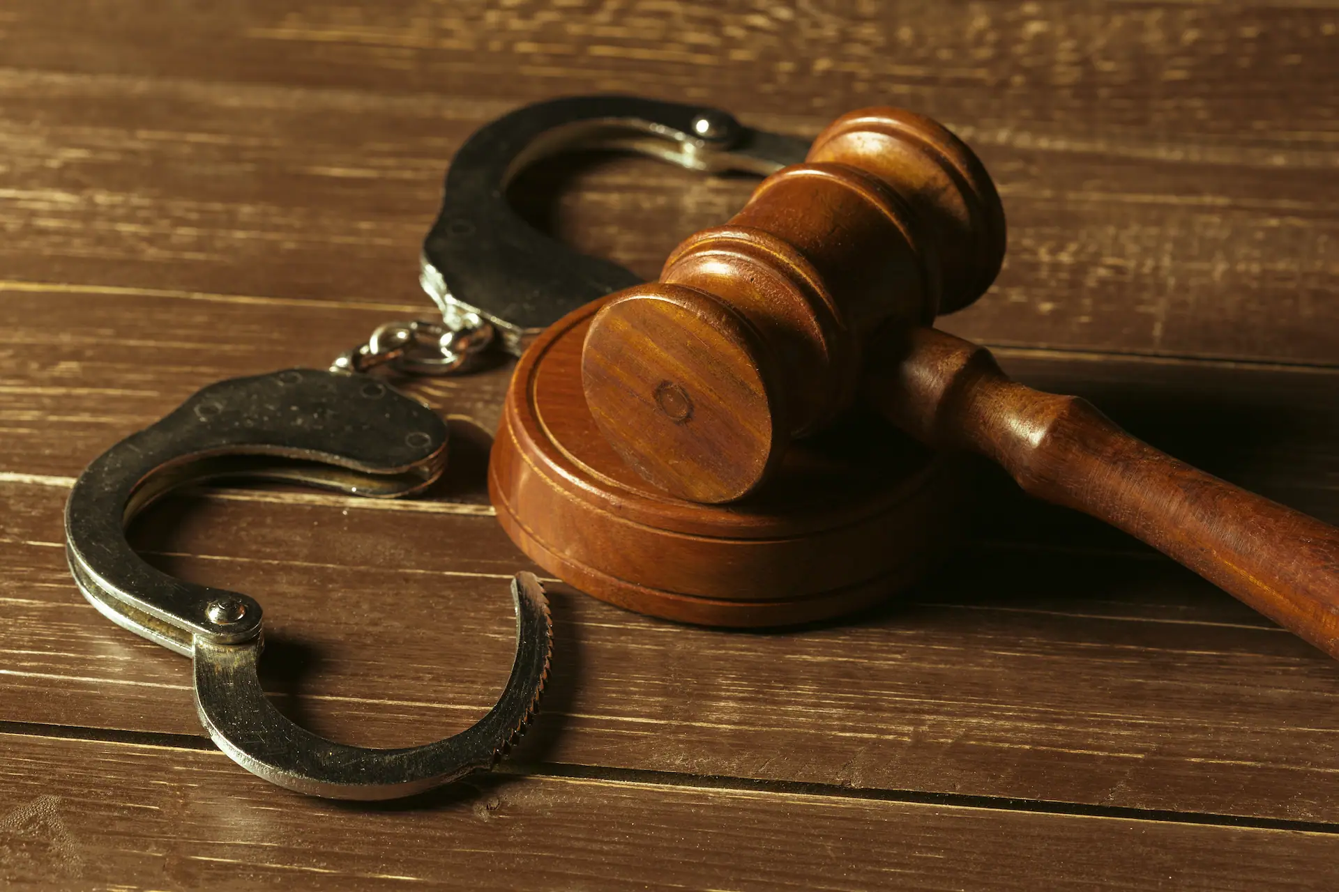 Kajdanki i sędziowski młotek na drewnianym stole – niesłusznie skazani i błędy sądowe